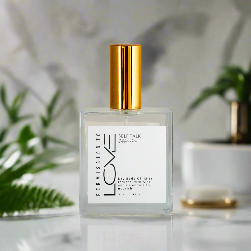 A bottle of Self Talk Dry Body Oil Mist with a white label and gold-colored cap.