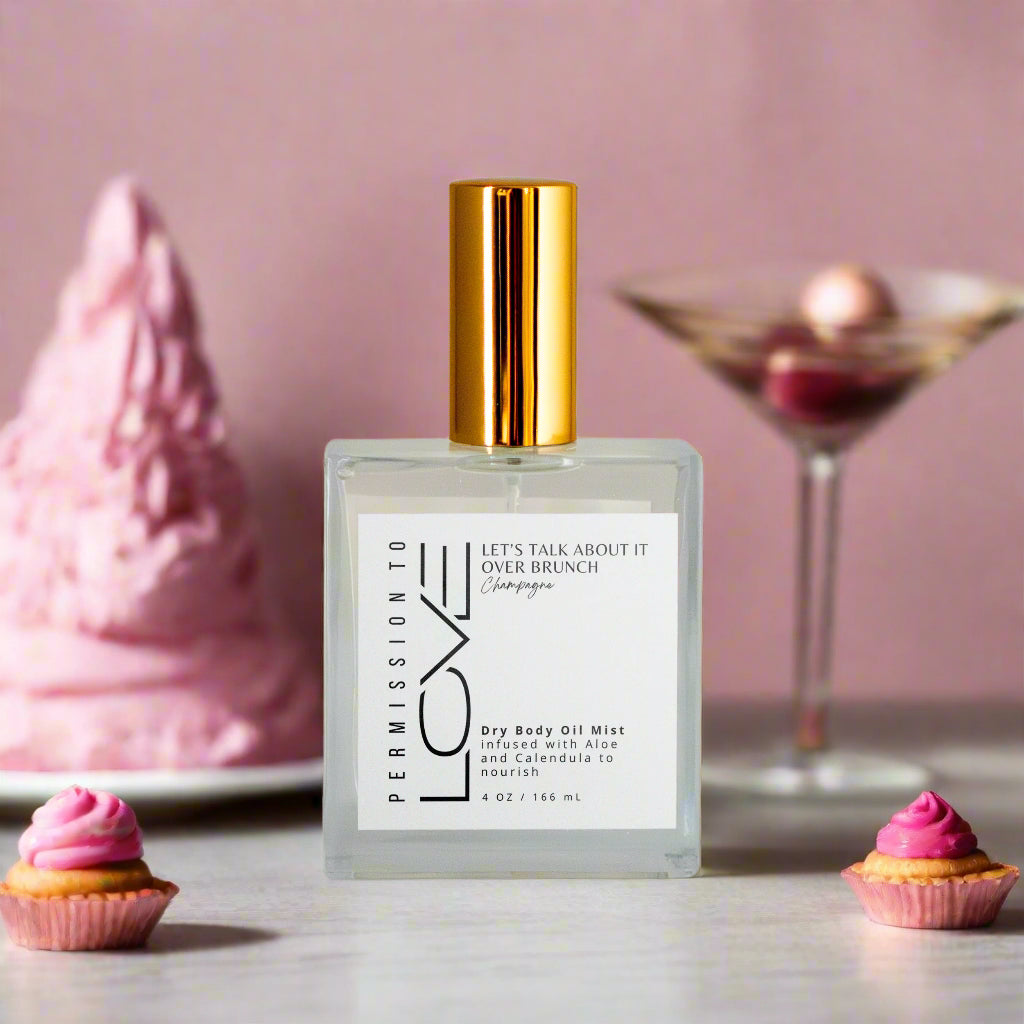A clear spray bottle with a gold cap labeled 'LOVE' representing the dry body oil body mist product.